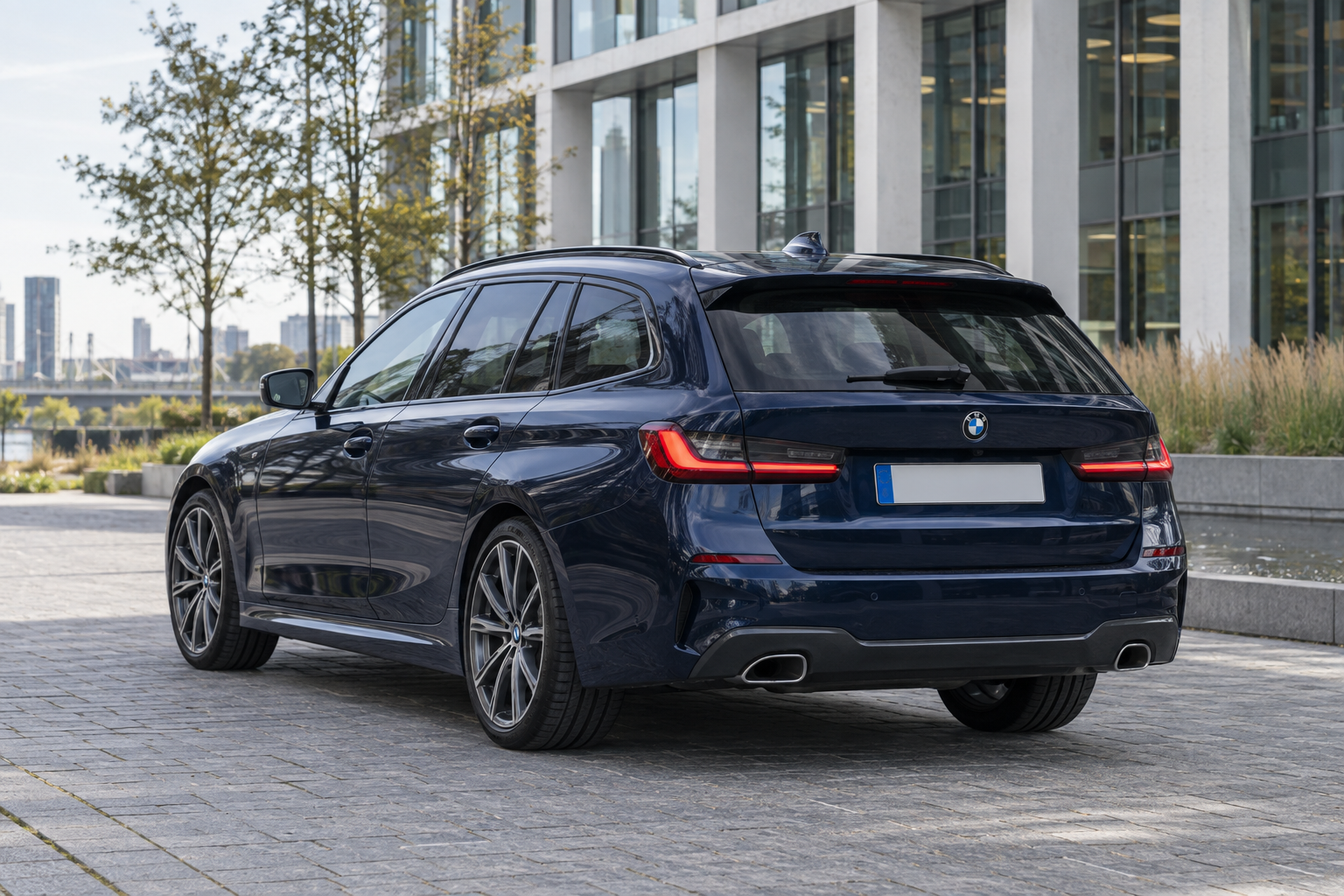Donkerblauwe BMW 3 Serie Touring bij een zakelijk gebouw
