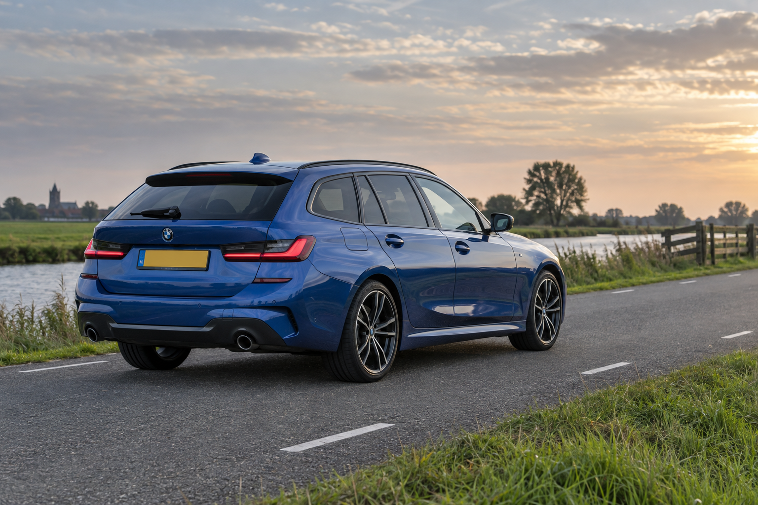 Blauwe BMW 3 Serie Touring met sportieve uitvoering langs een polderweg