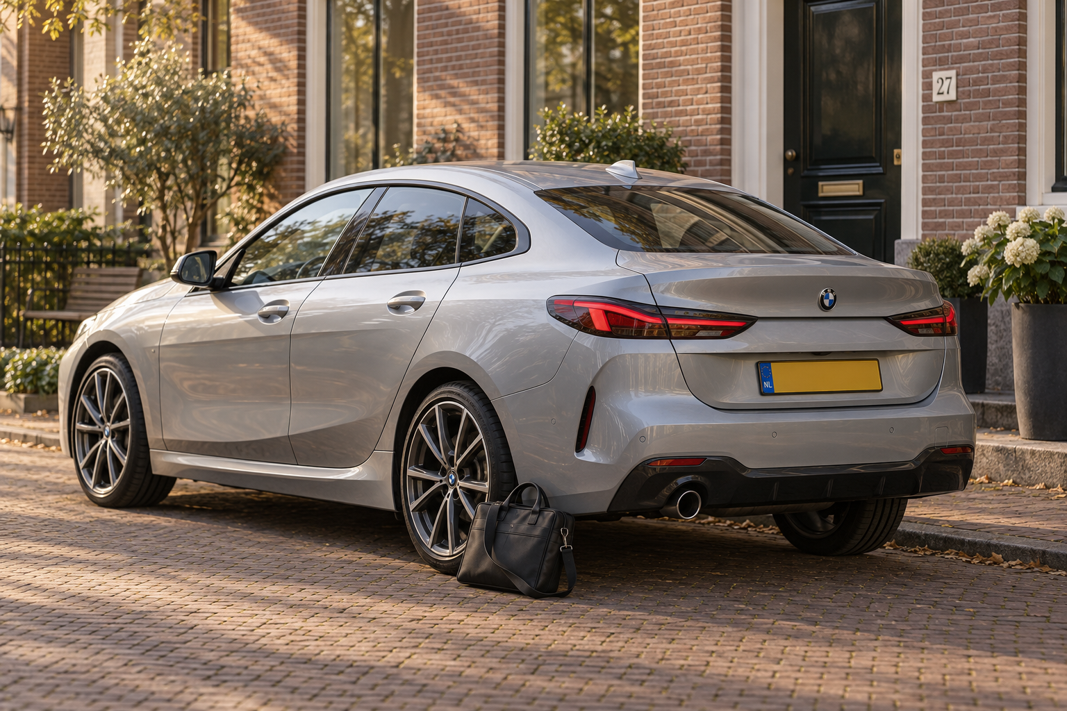 Zilverkleurige BMW 2 Serie Gran Coup&eacute; F44 met vier deuren, geparkeerd bij een woning met een werktas naast de auto