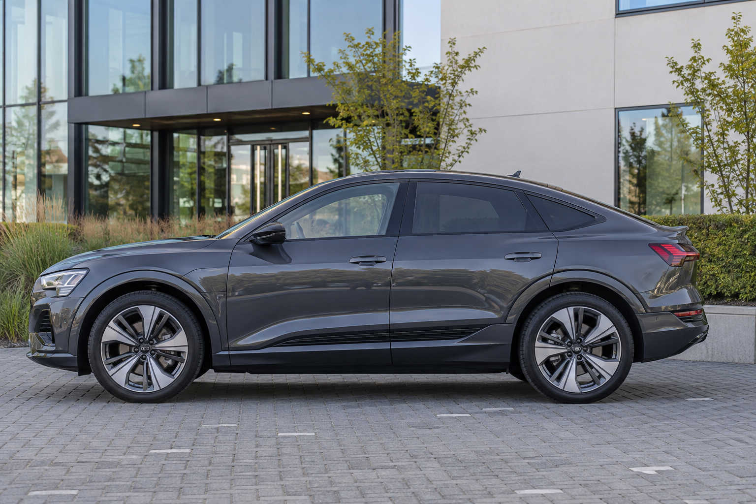 Zijaanzicht van een grijze Audi Q8 Sportback e-tron met aflopende daklijn