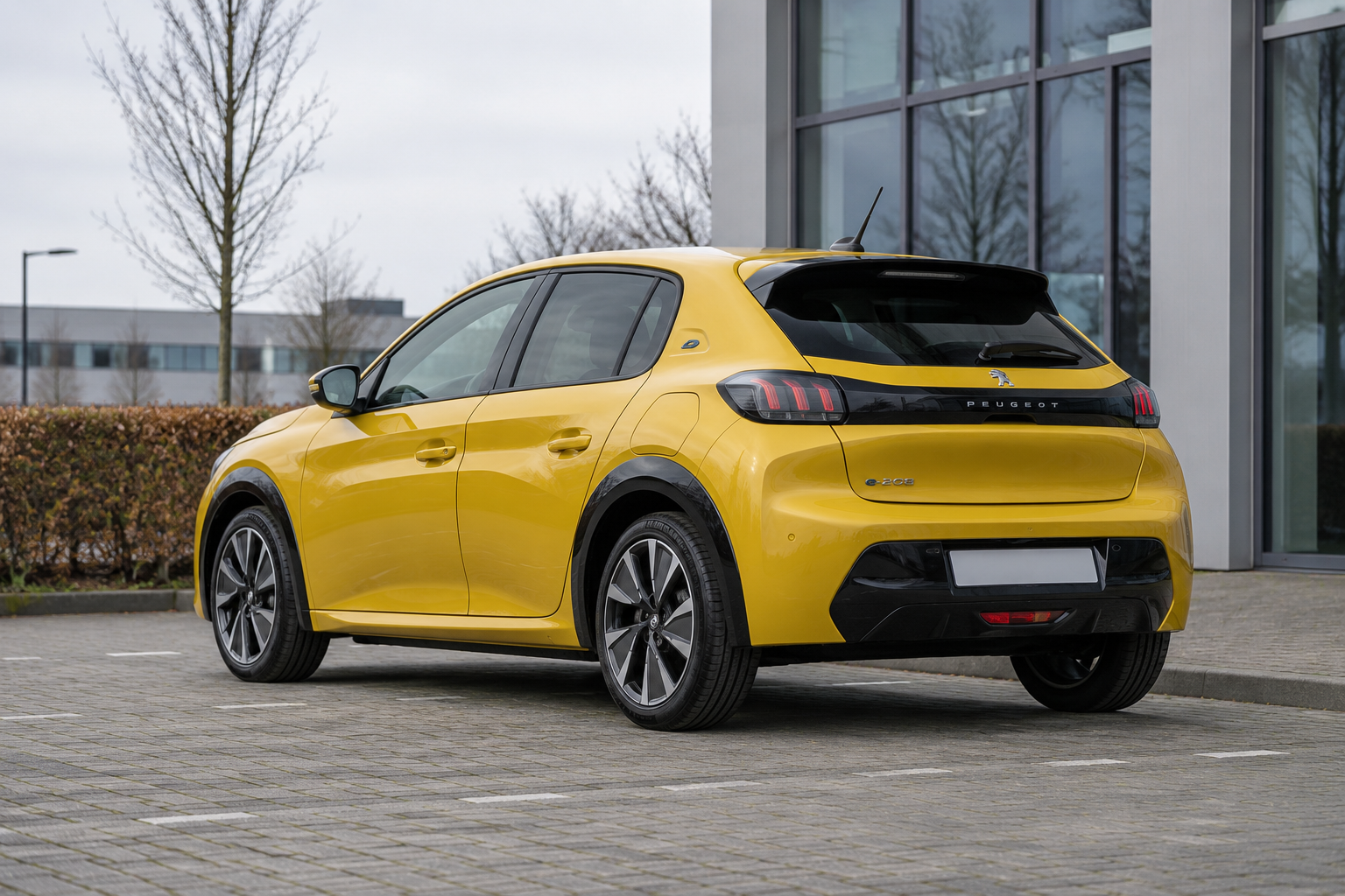 Peugeot E-208 gezien schuin van achteren bij een rustige parkeerplaats