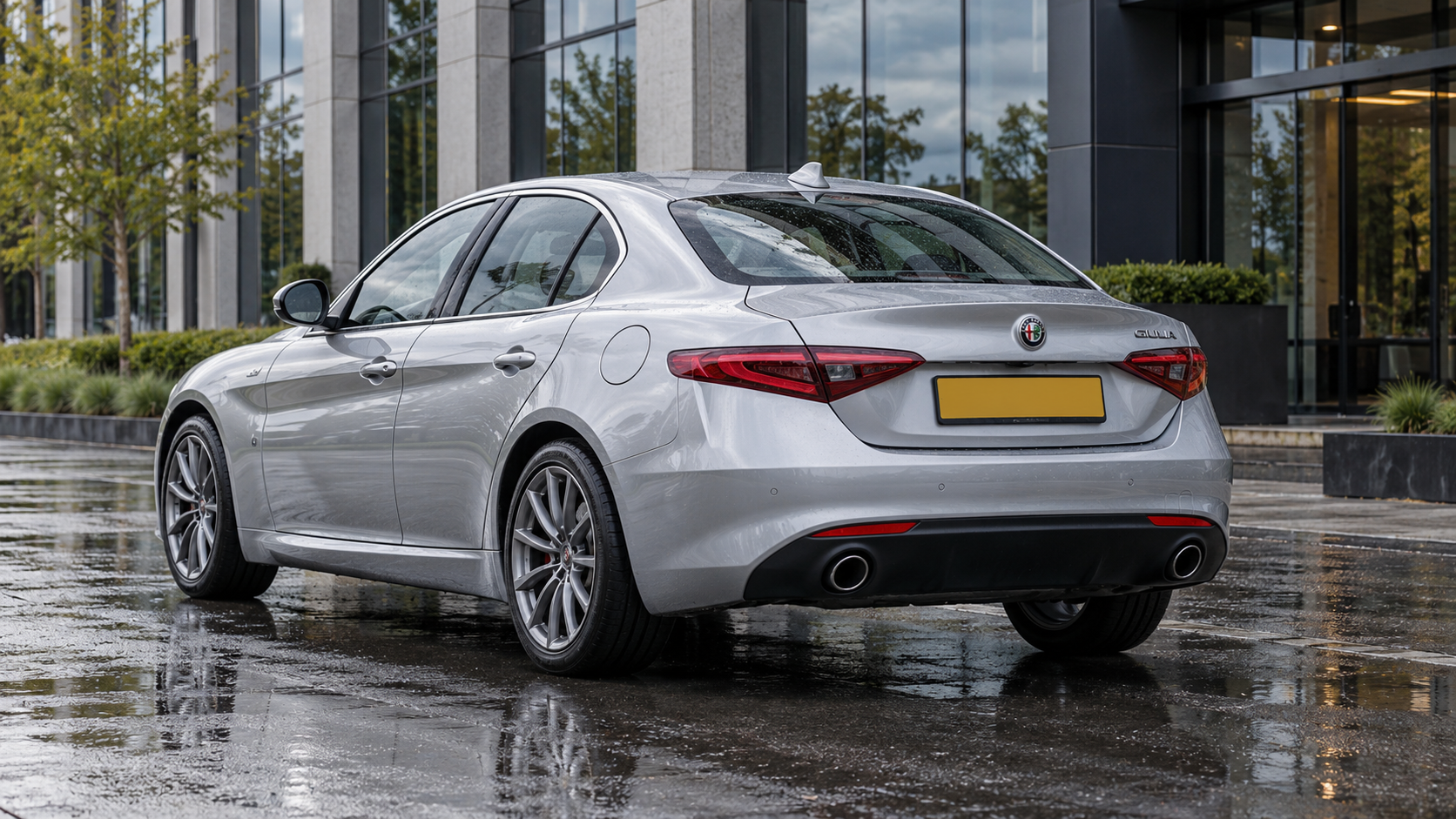 Zilverkleurige Alfa Romeo Giulia sedan van schuin achteren bij een kantoor