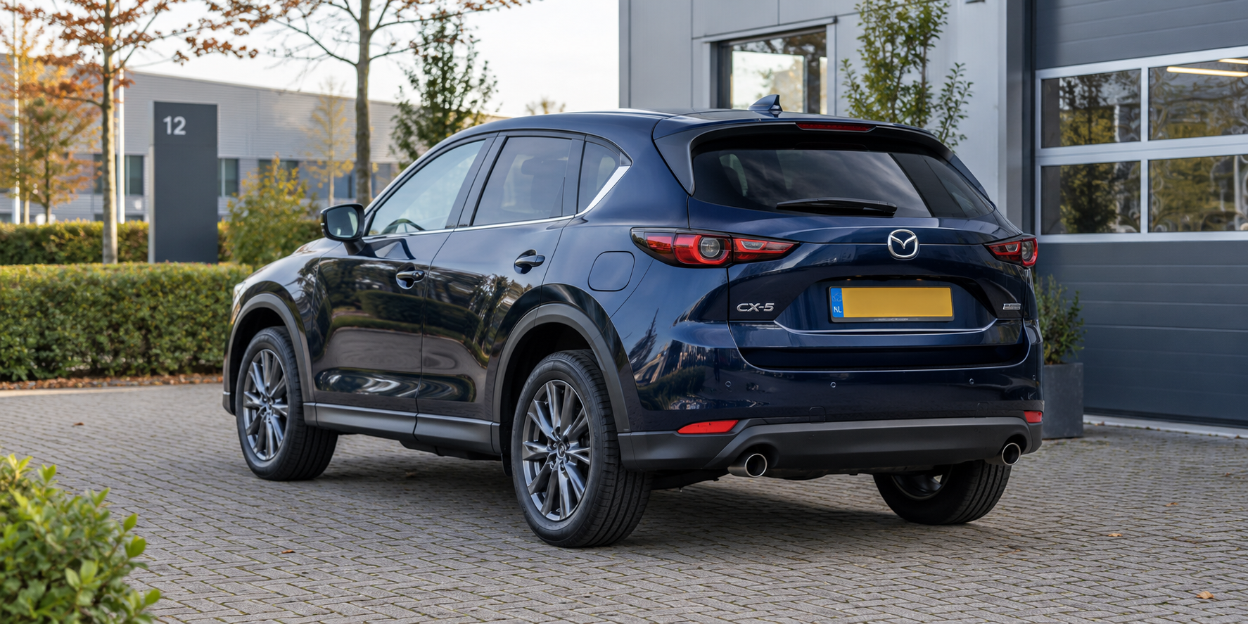 Blauwe Mazda CX-5 van de tweede generatie gezien van schuin achteren
