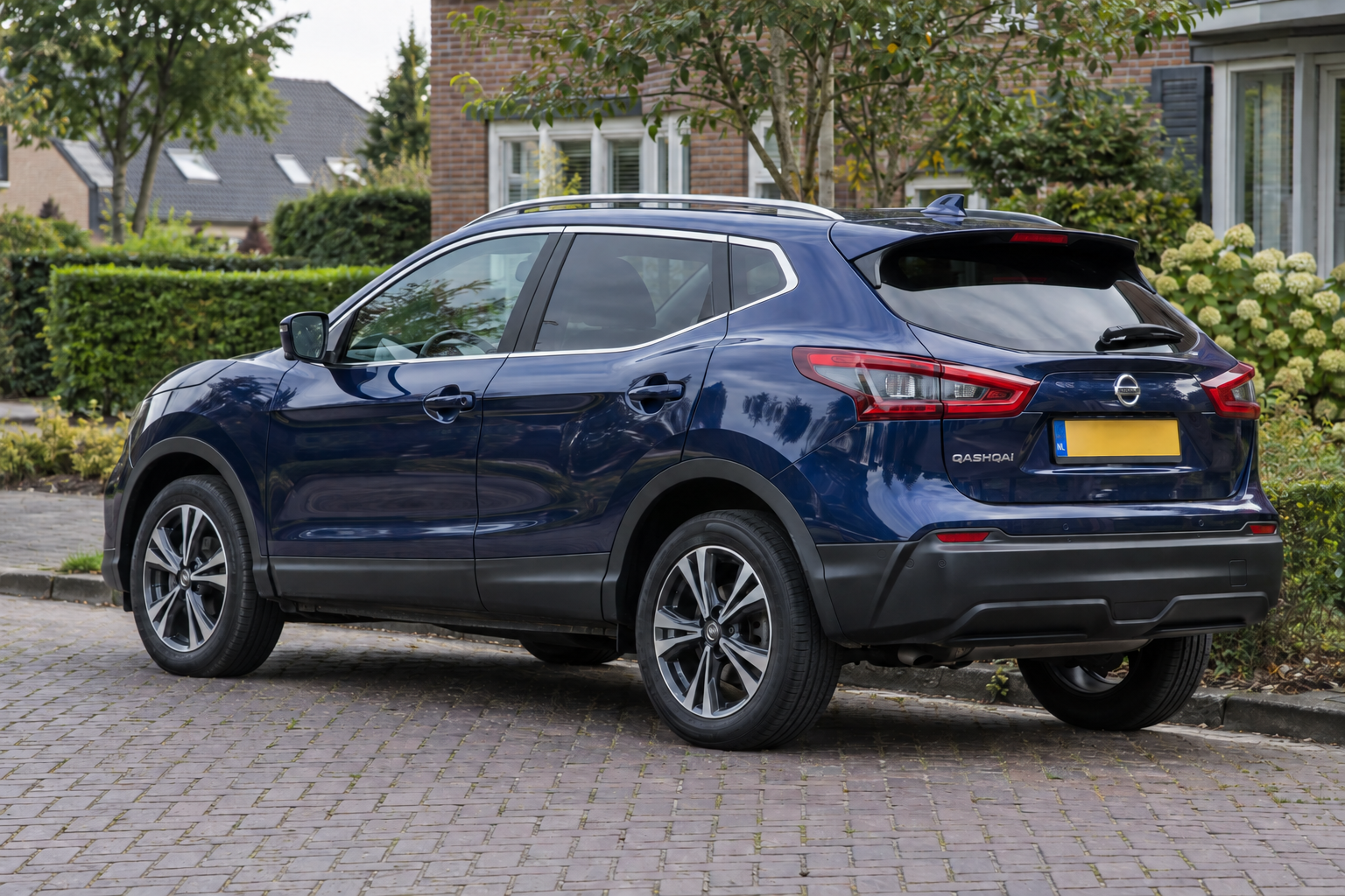 Blauwe Nissan Qashqai uit de J11-generatie gezien van schuin achteren