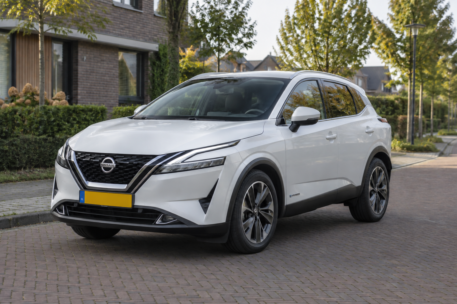 Witte Nissan Qashqai e-POWER van de derde generatie bij een kantoor