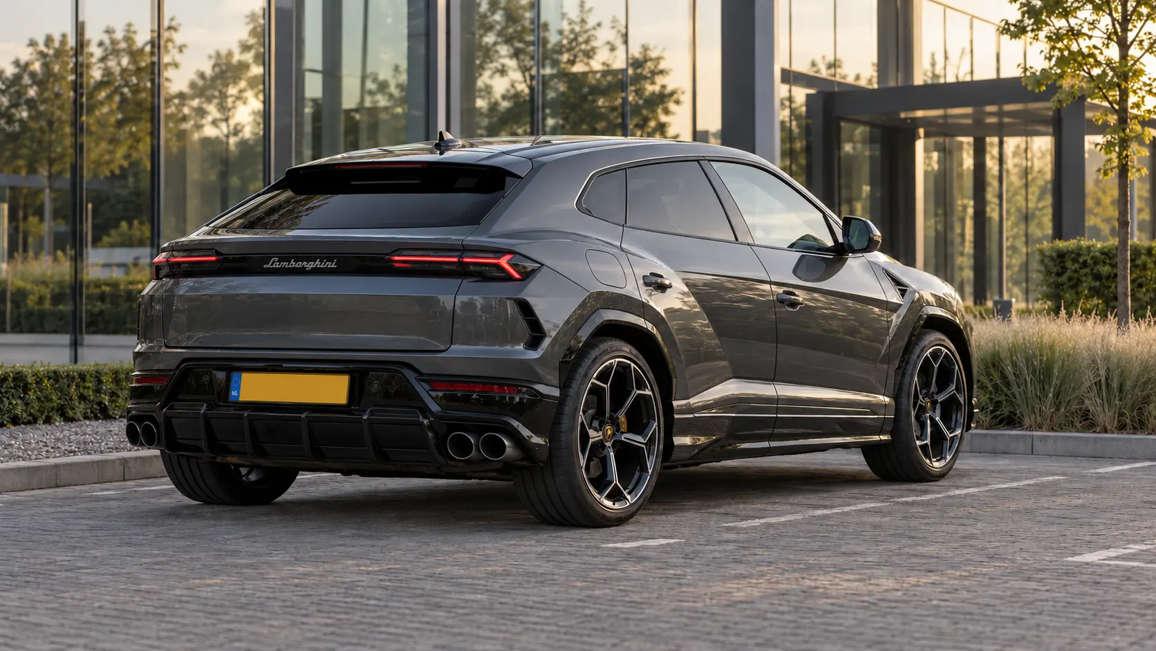 Donkergrijze Lamborghini Urus SE van achteren bij een zakelijke parkeerplaats