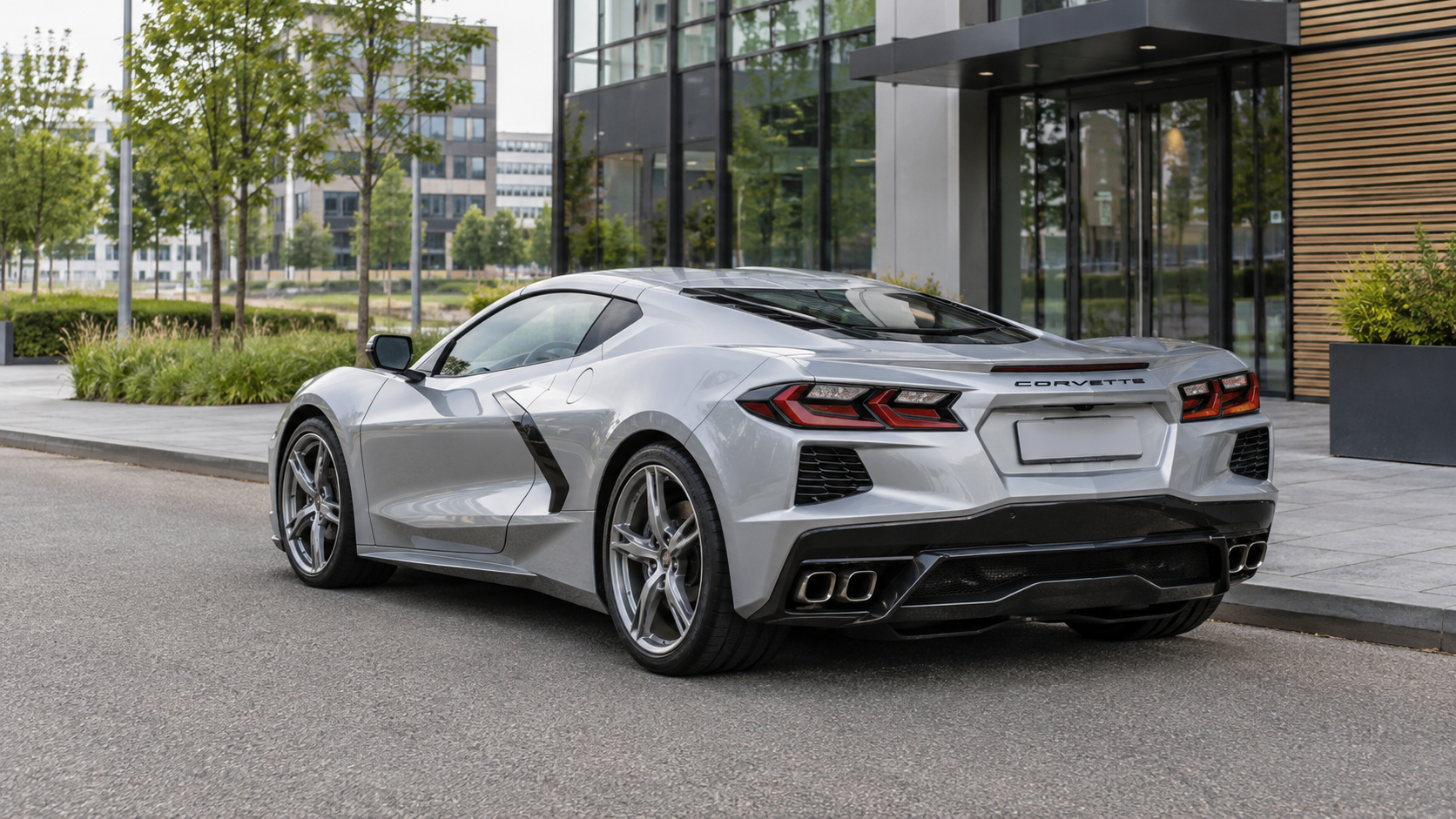 Zilveren Chevrolet Corvette C8 coup&eacute; van achteren bij een modern bedrijfspand